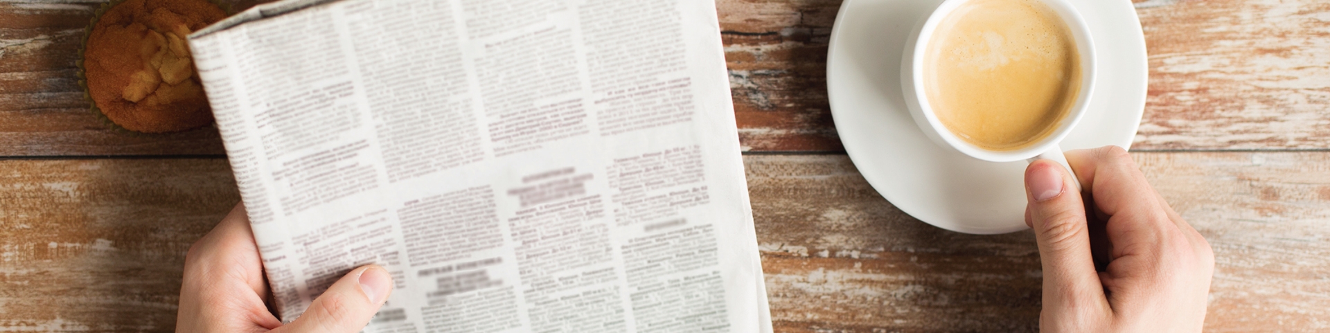 A man looking at a newspaper with coffee